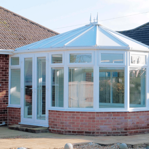 a brick building with a white roof and a white sunroom